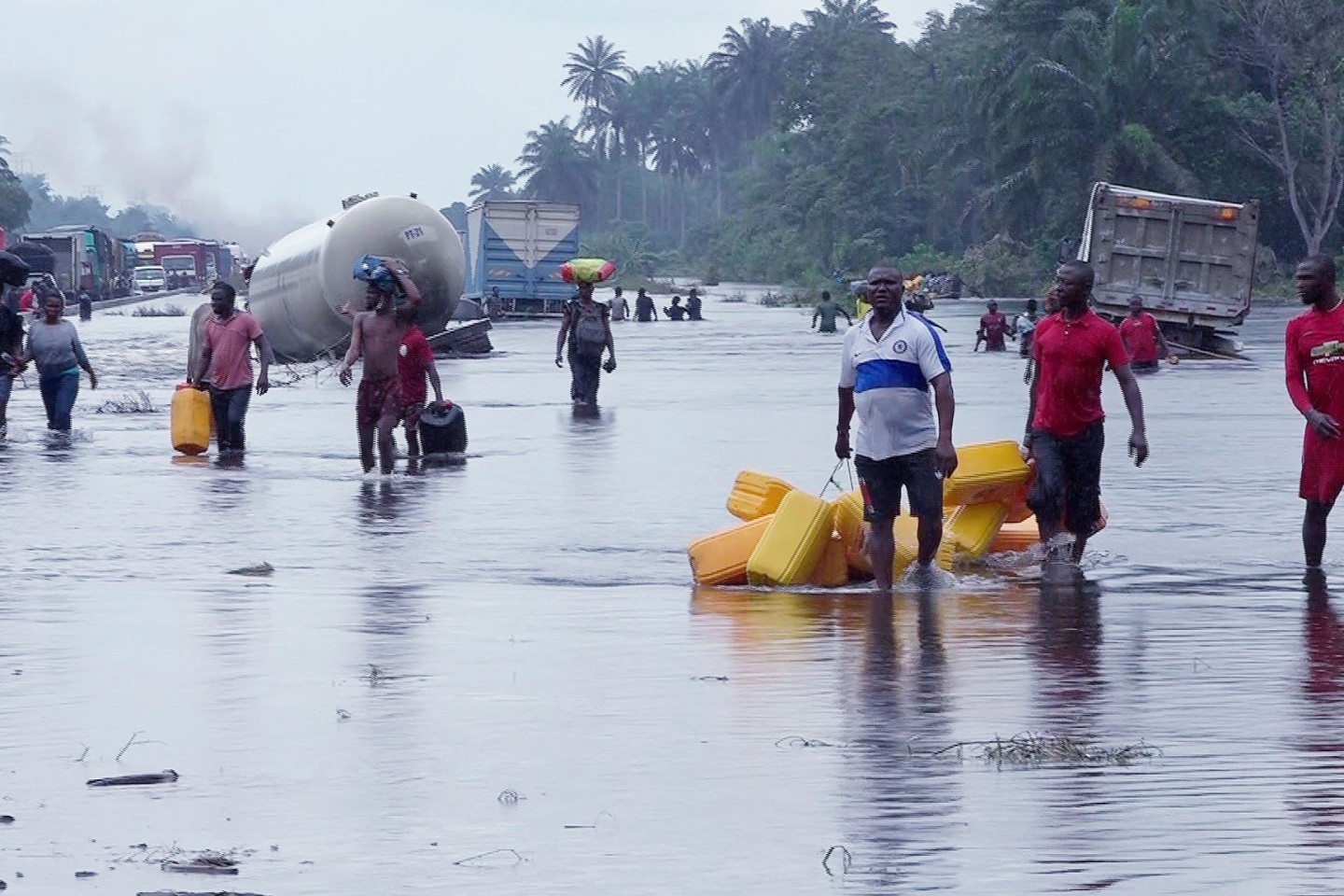 Menschen im nigerianischen Bayelsa waten durch überflutete Straßen.