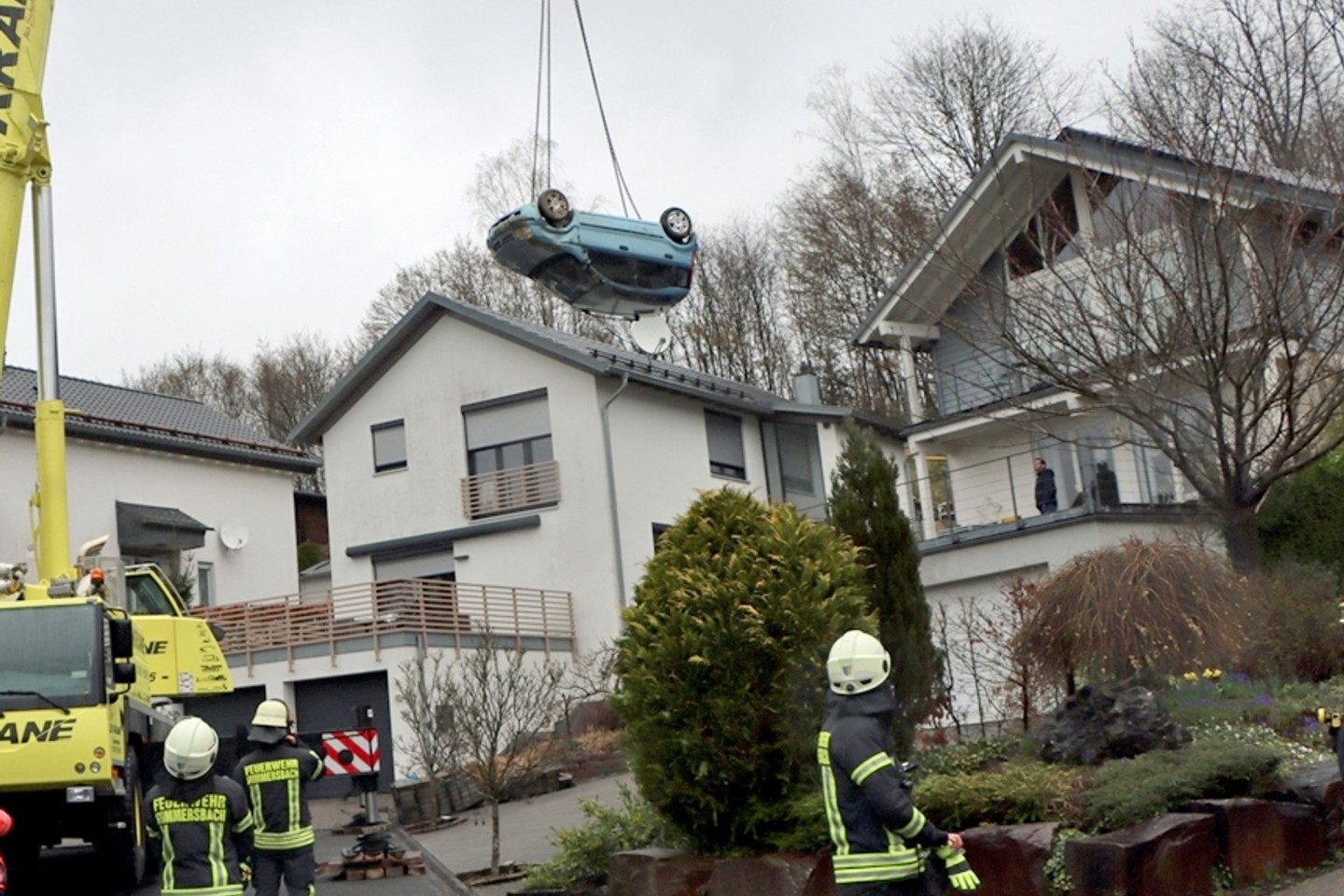 Ein Kranwagen hebt den verunglückten Kleinwagen von der Terrasse eines Einfamilienhauses in Gummersbach.