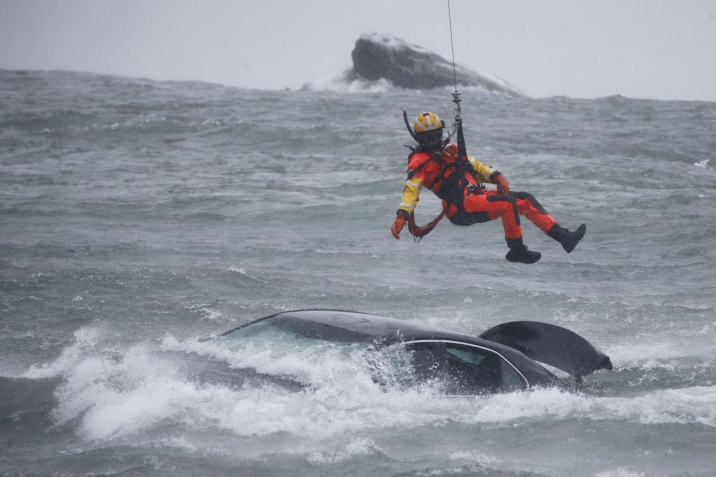 Ein Taucher der US-Küstenwache wird aus einem Hubschrauber abgelassen, um ein Opfer aus einem Fahrzeug zu bergen.