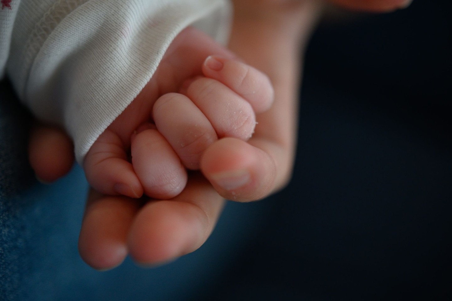 Die Hand eines zwei Wochen alten Neugeborenen liegt in der Hand seiner Mutter. In Großbritannien ist ein Baby mit dem Erbgut von drei Menschen geboren worden.