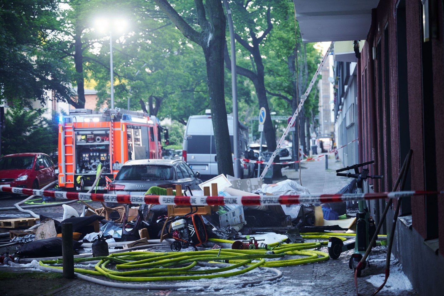 Verbranntes Mobiliar liegt auf einem Gehweg unterhalb einer ausgebrannten Wohnung in Berlin-Wilmersdorf.