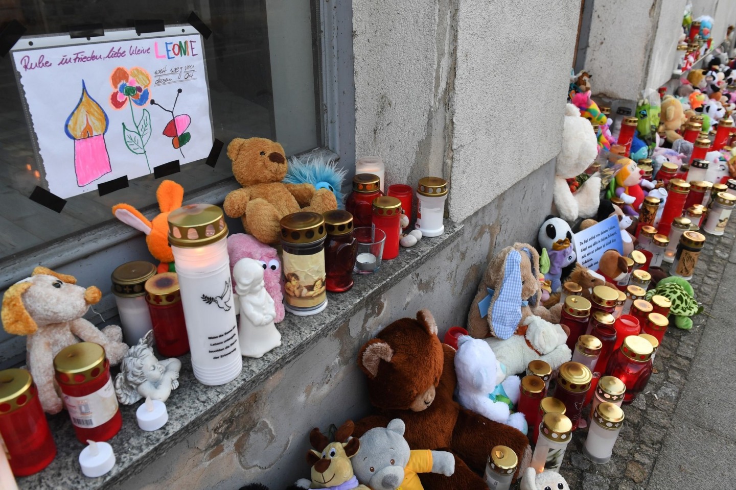 Kerzen und Plüschtiere stehen vor dem Eingang des Hauses, wo am 12.01.2019 die sechsjährige Leonie ums Leben kam.